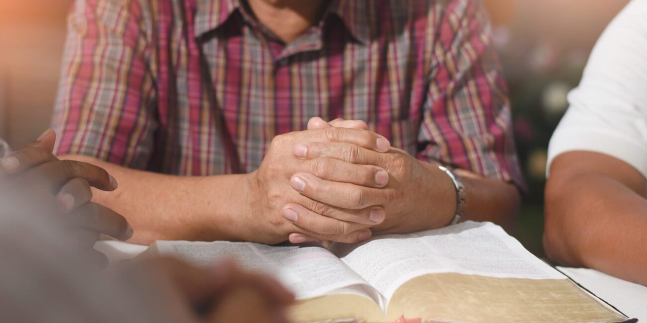 Person praying with bible infront